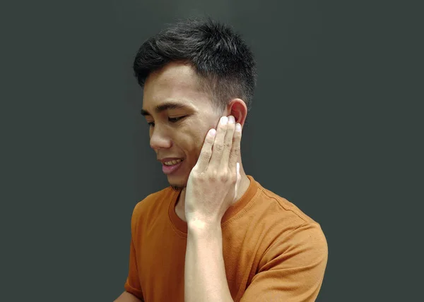 Man holding sore ear with hand. Aching ear pain concept