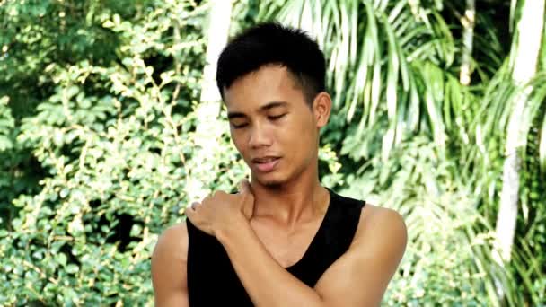 若いアジアの男性は アウトドアスポーツの後に肩をマッサージ — ストック動画