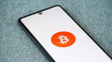 Akıllı telefon ekranında Bitcoin logosu. Sanal kripto para birimi kavramı 2025.