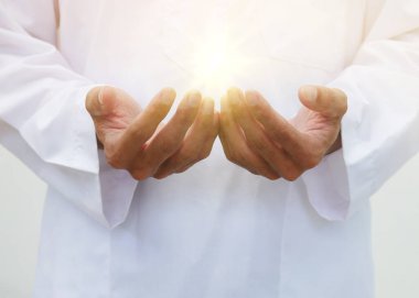 Müslüman bir adamın camide el kaldırması ve dua etmesi ön planda. Geleneksel Malay kıyafetleriyle ramazan ruhu..