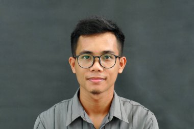 Gözlüklü ve kameraya bakan yakışıklı Asyalı bir adamın portresi.