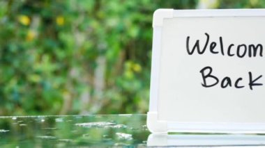 İş adamının elinde küçük bir karatahta var. Tekrar hoş geldin, arka planda doğa bokeh..