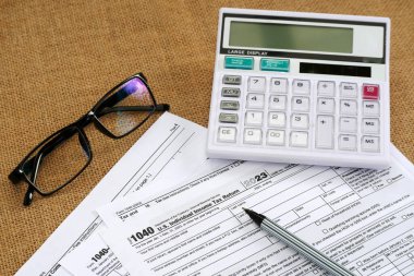 1040 Vergi Dönüş belgesi formunu hesap makinesi ve gözlüklü bir çuval bezi masasında