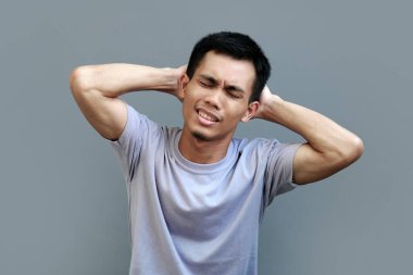 Endonezyalı erkek model iki eliyle kafasının arkasını tutuyor.