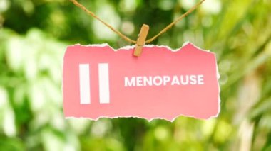 Üzerinde menopoz yazan pembe yırtık bir kağıt. İpte sallanıyor ve sallanıyor.