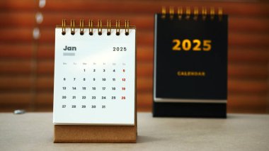 2025 Ocak 'ının masa takviminin arkasında altın 2025 masa takvimi var.