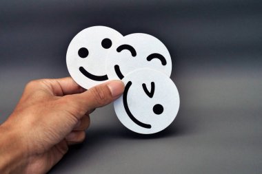 Karanlık Arkaplanda, Mutluluk, Eğlence ve Olumlu Duygular Üzerine Üç Beyaz Gülen Yüz Emojisi Tutmak