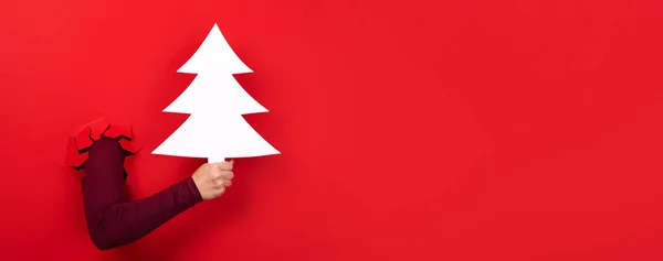 christmas tree in hand over red background, panoramic layout