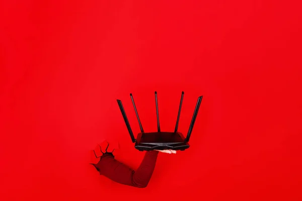 Elinde Kırmızı Arkaplan Üzerinde Siyah Kablosuz Yönlendirici Görüntünün Düzeni — Stok fotoğraf
