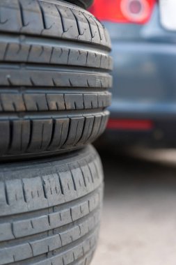 Arka planda bulanık bir araba, araba servisi veya bakım temaları için ideal olan, aşınmış ve yeni lastikleri gösteren yakın çekim.