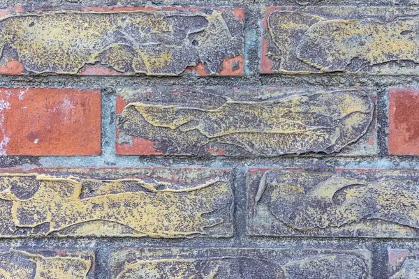 Sarı ve kahverengi kabuklu yıpranmış tuğla bir duvara yakın çekim, yaşlı dokuyu ve kırsal karakteri ortaya çıkarıyor..