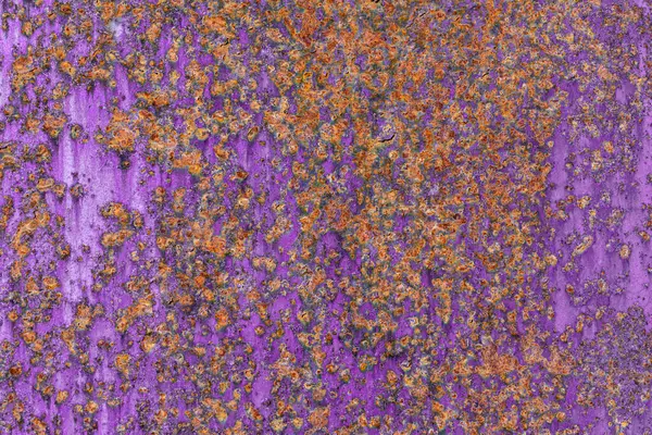 Paslanmış, mor boyalı, turuncu paslı metal bir yüzeye yakın çekim yaparak canlı ve desenli bir endüstriyel zemin oluşturur..