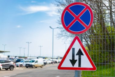 Yol kenarı tabelasına göre park yeri ve çift yönlü trafik yok. Açık bir gökyüzünün altındaki kalabalık bir park alanının yakınındaki çitlere monte edilmiş..