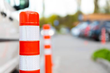 Sokakta yansıtıcı çizgileri, bulanık arabaları ve arka planda kaldırımları olan turuncu bir trafik kordonunun yakın çekimi.