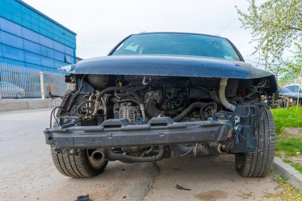 Ön tamponu ve ön parçaları sökülmüş, motor, hortum ve mekanik parçaları ortaya çıkmış bir arabanın ön görüntüsü..