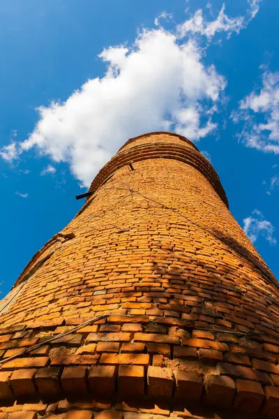 Eski silindirik tuğla bir kule alçak açılı görüş görünür çatlaklar, dağınık bulutlar ile canlı mavi bir gökyüzü karşı kurulmuş.