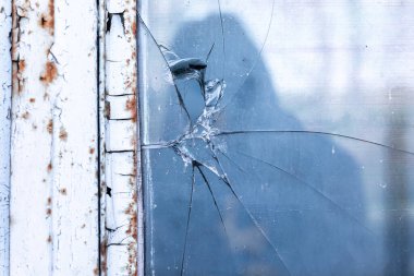 Paslanmış ve soyulan beyaz metal çerçeveli cam kırıklarının yakın çekimi hasar ve yıpranma gösteriyor..