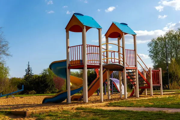 Güneşli mavi gökyüzünün altında slaytlar, köprüler ve kumla kaplı açık hava oyun parkı aile ve çocukluk teması için ideal..