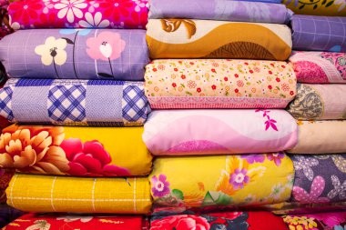 Sanatsal çeşitlilikte tonlama renkleri satılmak üzere perakende mağaza rafına istiflenmiş yatak çarşafları