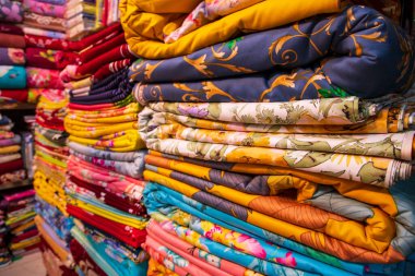 Sanatsal çeşitlilikte tonlama renkleri satılmak üzere perakende mağaza rafına istiflenmiş yatak çarşafları