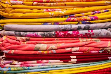 Sanatsal çeşitlilikte tonlama renkleri satılmak üzere perakende mağaza rafına istiflenmiş yatak çarşafları