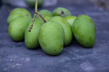 Yakın plan Beton zeminde taze çiğ yeşil mango odağı