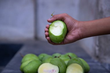 Bulanık arkaplanı olan çiğ yeşil mango ısırığı.