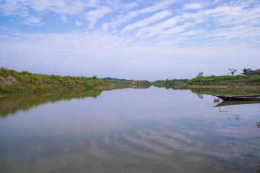 Bangladeş 'teki Padma nehrinin yakınındaki suya yeşil çimen ve bitki örtüsü yansıyan kanal