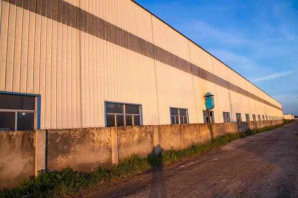 stock image Industrial evening sunlight reflecting on the industrial warehouse  against the blue sky landscape view