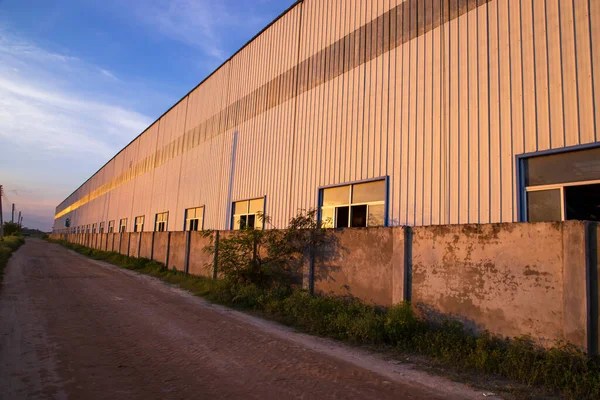 青い空の景色に対する産業倉庫に反射する産業用の夜の日差し — ストック写真