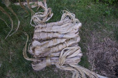 A thick brown  bundle of raw jute has on the ground