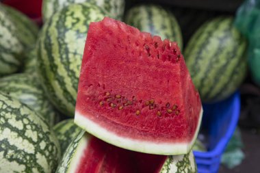 Yakından bakınca yaz sıcağında pazarda bir dilim kırmızı karpuz satılıyor.