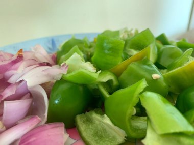 Beyaz arka planda doğranmış taze yeşil dolmalık biber (capsicum) ve soğan. Taze yeşil dolma biberin (capsicum) beyaz arkaplanda üst görünümü.