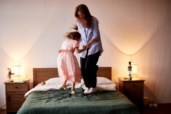 Little caucasian girl have fun with mother. Jumping on bed christmas morning. Happy family christmas concept