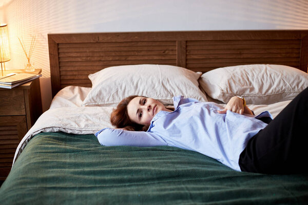 Уютный портрет женщины тысячелетия, отдыхающей на уютной кровати. Спальня с современным интерьером