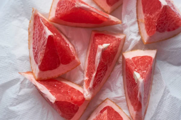grapefruit cut in pieces on white paper background