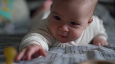 Küçük bebek karnının üstünde yatıyor. Yeni doğmuş bebek ve eğitici oyuncak