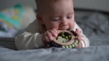 Bebek teether oyuncağı. İlk dişi büyüyen bebek. Çocuk ebeveyn yatağında oyuncak ısırıyor. Altı aylık güzel bir erkek bebek. Gerçekçi bebek ev portresi