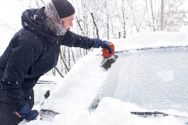 男は雪の後に車を掃除する フロントガラスからの雪のクリーニング 氷のスクレーピング 冬の車の窓のクリーニング — ストック写真
