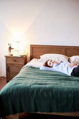 Milenyum dişisinin rahat bir yatakta rahatlamasının samimi bir portresi. Modern odalı bir yatak odası.