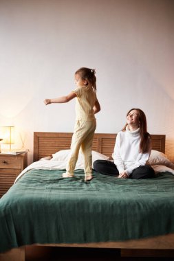 Little caucasian girl have fun with mother. Jumping on bed christmas morning. Happy family christmas concept