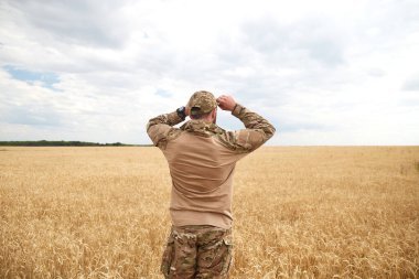 Ukrainian military man in wheat field. Ukrainian wheat fields and war upcoming food crisis. Armed Forces of Ukraine