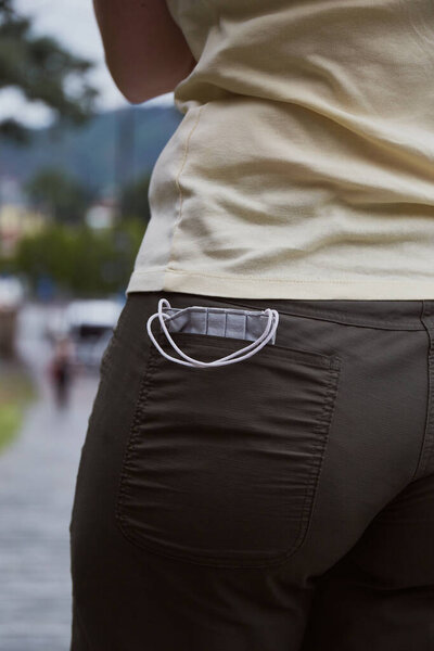 Medical face mask in back pocket. Concept for the tourism during pandemic