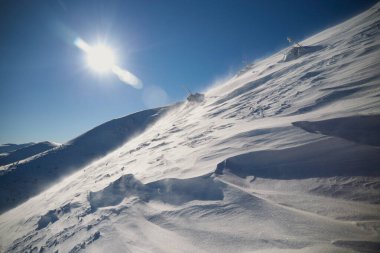 Snow texture. Strong wind in Carpathian mountains in winter on a sunny day. Wind sculpted patterns on snow surface clipart
