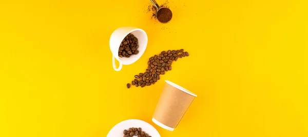 eco friendly coffee accessories. White coffee cup and paper cup with beans and melted coffee. Yellow background. Copy space