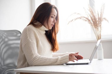 Young business woman sitting at desk working online on laptop. Company employee worker 