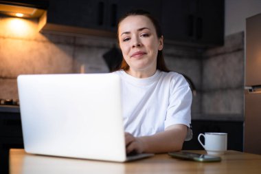 Work on the kitchen office. Remote work from home office. Young woman using laptop. Freelancer workplace at kitchen table. Distance education