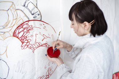 Kadın ressam boya fırçası ve siyah boyayla resim çiziyor. Grafik boyama. Modern sanat yaratılıyor