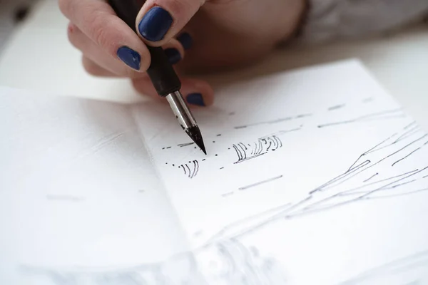 Kadın ressam çizimlerine kalem ve siyah mürekkeple bakıyor. Grafik boyama. Modern sanat yaratılıyor