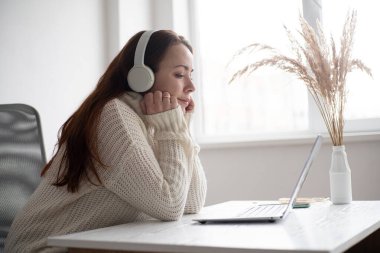 Beyaz kadın laptopuyla video görüşmesi yapıyor. Modern ofiste kızıl saçlı kadın.